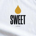 Близък план на принта Sweet със златна капка мед върху бяла тениска noDRAMA