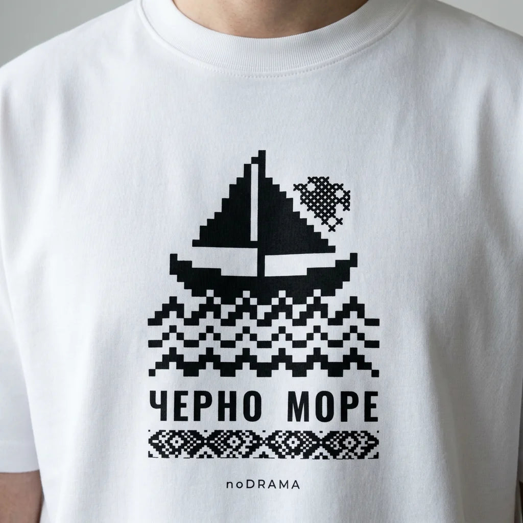 Близък план на щампата Черно море с платноходка и шевица върху бяла тениска noDRAMA