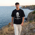 Мъж с черна oversized тениска Сократ на скалите над морето noDRAMA