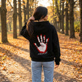 Жена в черен oversized суитшърт с длан на гърба