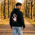 Мъж в черен oversized суитшърт с длан и „любов“ на гърба, есенен парк